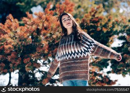 Young woman enjoying the snowy mountains in winter with her arms open, in Sierra Nevada, Granada, Spain. Female wearing winter clothes.. Young woman enjoying the snowy mountains in winter