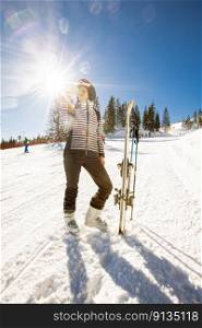 Young woman enjoying winter day of skiing on the snow covered slopes, surrounded by tall trees and dressed for cold temperatures