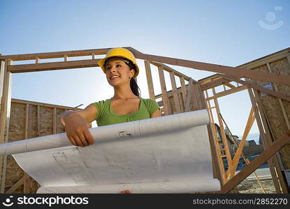 Young woman examining blueprint in construction site