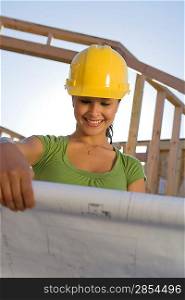 Young woman examining blueprint in construction site