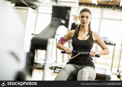 Young woman exercises on an exercise machine at the gym listening to music
