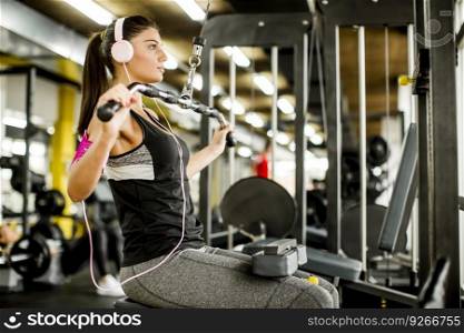 Young woman exercises on an exercise machine at the gym listening to music