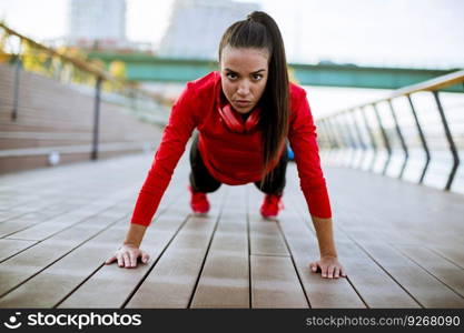 Young woman exercises on the promenade after running in the morning