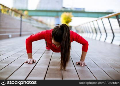 Young woman exercises on the promenade after running in the morning