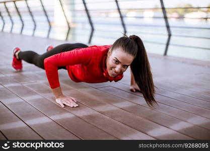 Young woman exercises on the promenade after running in the morning