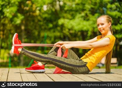 Young woman exercises outdoor in park, using gym accessory, resistance band, strap elastic. Staying fit and healthy.. Girl doing exercise outdoor, using resistance fit band.