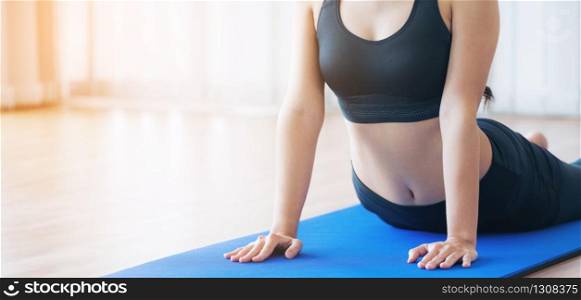 Young woman exercising in indoor gym on yoga mat. Healthy lifestyle and wellness concept.