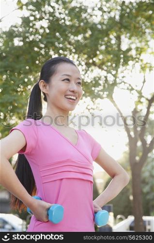 Young Woman Exercising in Park with Dumbells