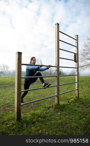 Young Woman Exercising On Outdoor Gym Equipment In Park Stretching On Bars