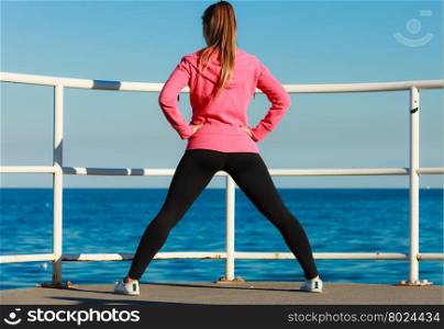 Young woman exercising outside. Sports and activities concept. Slim fit attractive woman exercising stretching outdoor. Young motivated girl training in sporty clothes.