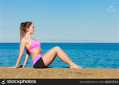 Young woman exercising outside. Sports and activities concept. Slim fit attractive woman exercising stretching outdoor. Young motivated girl training in sporty clothes.