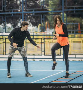 Young woman exercising with personal fitness coach using agility ladder. Agility skill improvement.. Young Woman Exercise using Agility Ladder, working with Fitness Coach