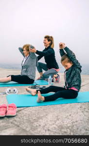 Young woman exercising with senior woman and little girl. Women exercising with little girl