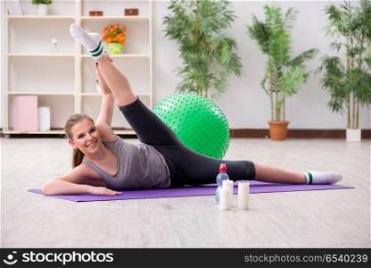 Young woman exercising with stability ball in gym