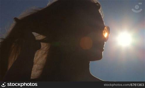 Young woman face in sunglasses against the sun lens flare