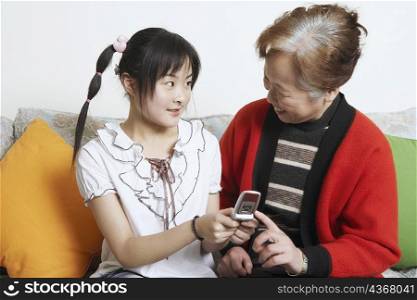 Young woman facing her grandmother holding a mobile phone