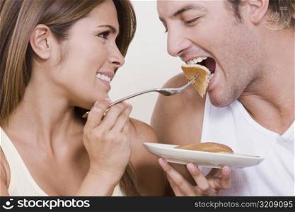 Young woman feeding breakfast to a mid adult man