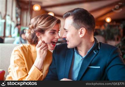 Young woman feeding man with a spoon in restaurant. Love cople at romantic dinner. Young woman feeding man with a spoon