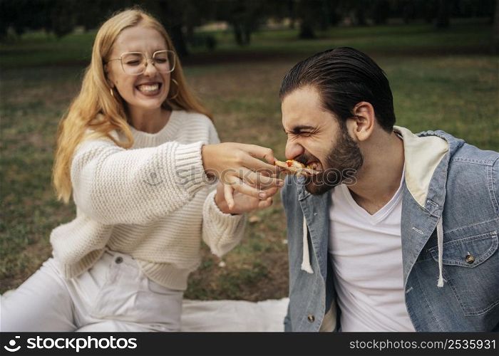 young woman feeding pizza her boyfriend