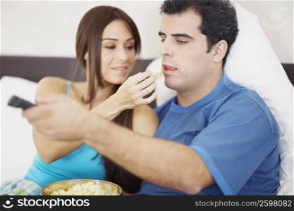 Young woman feeding popcorn to a mid adult man