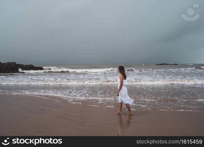 Young woman feeling lonely and sad looking at the sea on a gloomy day