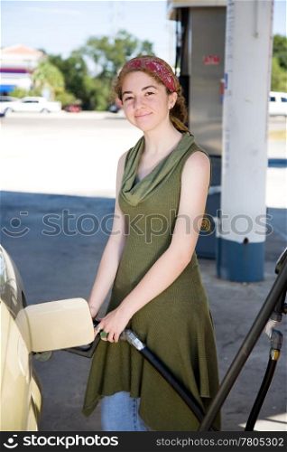 Young woman filling up her gas tank is smiling because she drives a fuel efficient car.