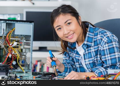 young woman fixing a desktop computer seated at a table