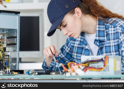 young woman fixing a desktop computer seated at a table