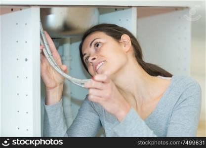 young woman fixing sink pipe in kitchen