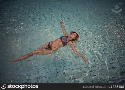 Young woman floating in the pool on her back