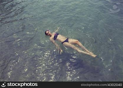 Young woman floating on her back in lake