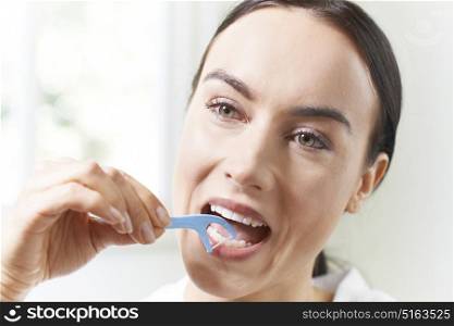 Young Woman Flossing Teeth In Bathroom