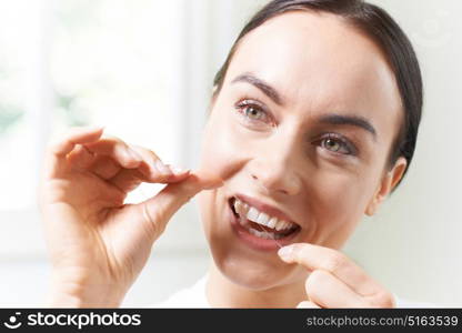 Young Woman Flossing Teeth In Bathroom