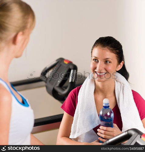 Young woman friends exercising in fitness center on treadmill machine