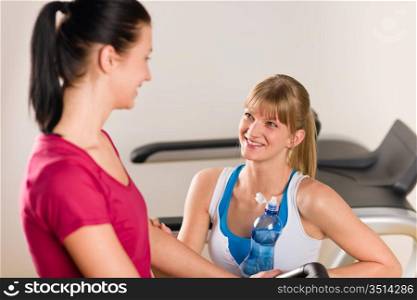 Young woman friends exercising in fitness center on treadmill machine