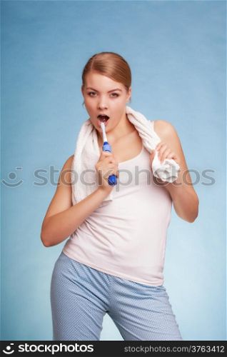 Young woman funny girl singing to toothbrush brushing her white teeth doing fun on blue. Daily dental care. Studio shot.