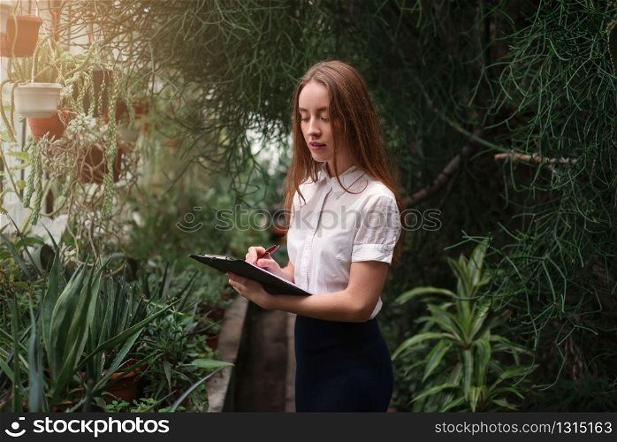 Young woman gardening in greenhouse. Plants and flowers business concept.