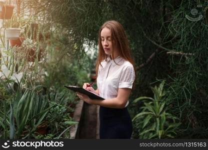 Young woman gardening in greenhouse. Plants and flowers business concept.