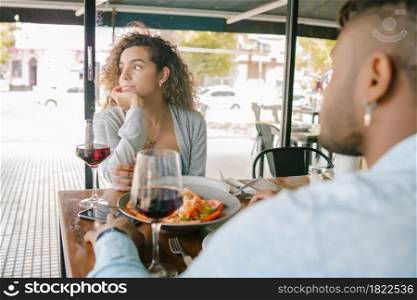 Young woman getting bored at a lunch date with a man at a restaurant. Relationship concept.