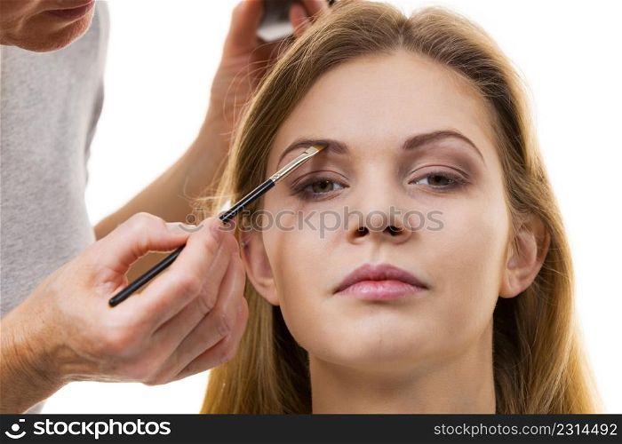 Young woman getting her eyebrow make up done by professional visage artist. Person using brush to paint eyebrows.. Woman getting eyebrows make up done