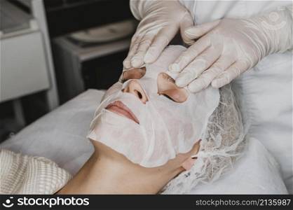 young woman getting skin mask treatment spa
