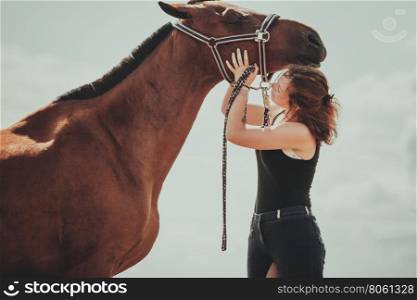Young woman girl taking care of horse.. Young woman girl taking care of brown horse. Female with animal outdoor.