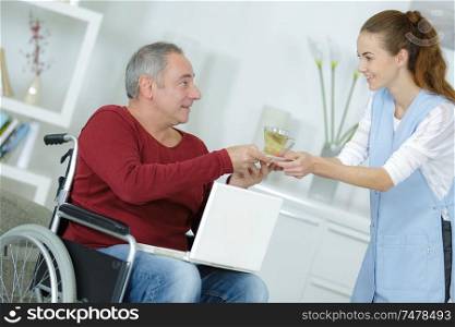 young woman giving a glass of water to disabled man