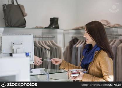 Young woman giving credit card to cashier