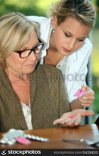 Young woman giving her grandmother medicine