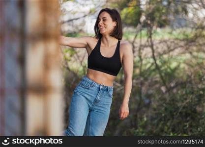 Young woman grabs ancient metal fence in a ancient industrial street, freedom concept