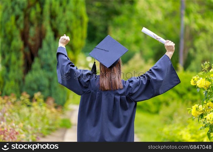Young woman graduate put her hands up and celebrating with certificate in her hands and feeling so happiness in. Young woman graduation day images of graduates are celebrating g