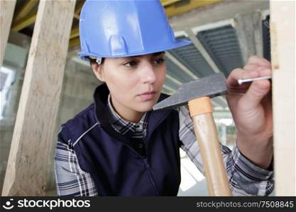 young woman hammering nail in wall