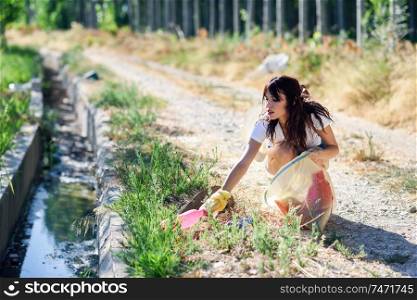 Young woman hand collecting garbage of the grass in the countryside. Woman hand collecting garbage of the grass in the countryside