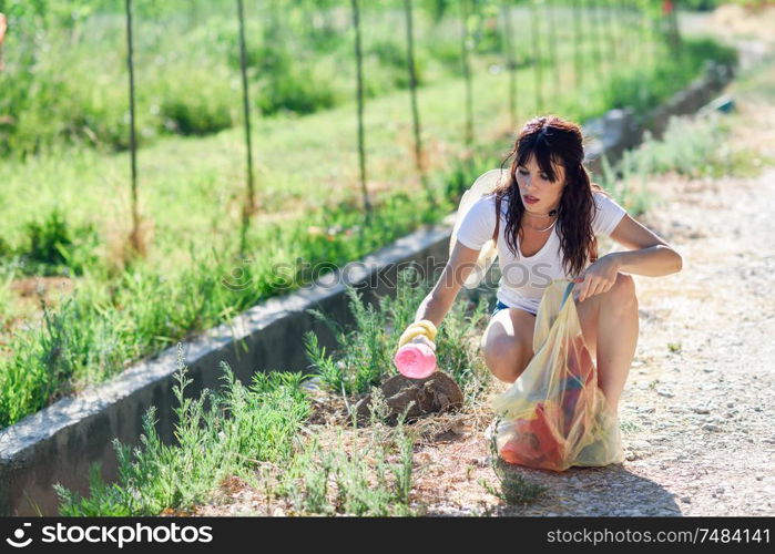 Young woman hand collecting garbage of the grass in the countryside. Woman hand collecting garbage of the grass in the countryside